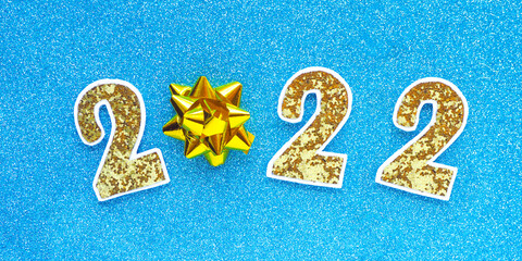 2022 in gold numbers and a gift bow on a bright red glitter background..