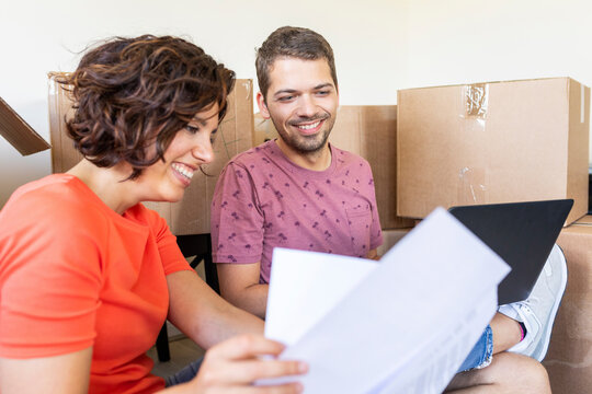 Happy couple in new home with documents and laptop
