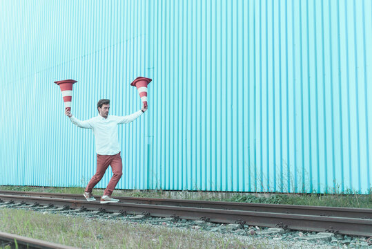 Young man balancing on rails, juggling traffic cones