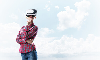 Girl in checked shirt wearing VR glasses experiencing another reality