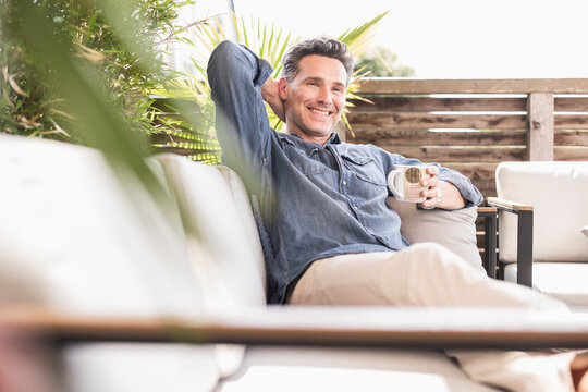 Confident man relaxing on the terrace, drinking coffee