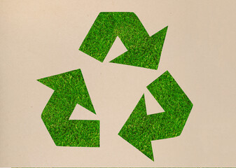 Waste Recycling - symbol - green Eco recycle sign made of craft paper on green grass background top view