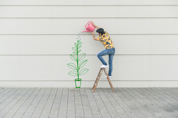 Digital composite of young man watering flower at a wall