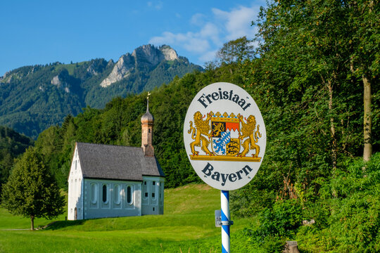 Germany, Bavaria, Nussdorf, State border information sign with Kreuzkirche in background