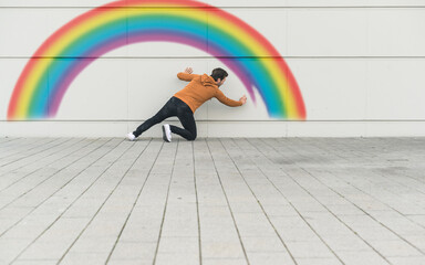 Digital composite of young man painting a rainbow at a wall