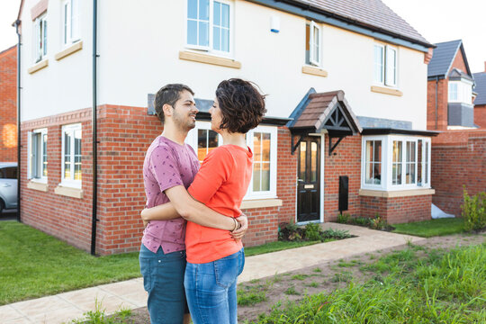 Happy couple hugging in front of their new home