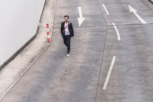 Confident businessman walking on road with arrow signs