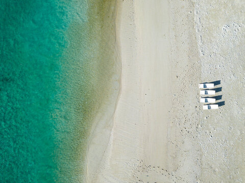 Empty sunloungers at tropical beach, aerial view
