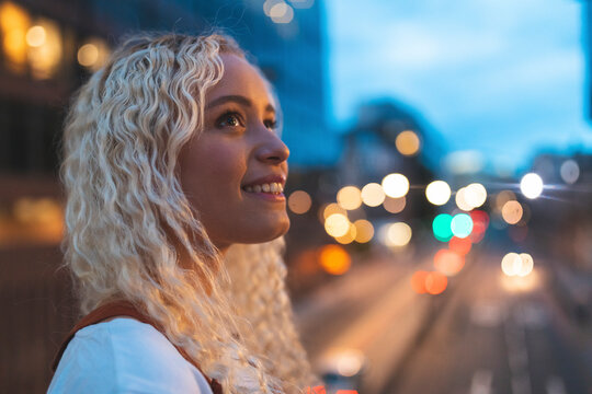 Young woman in the city at dusk with busy urban street in London