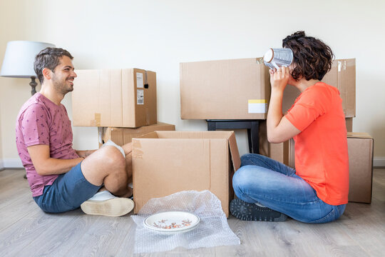 Happy couple moving into new home unpacking cardboard box