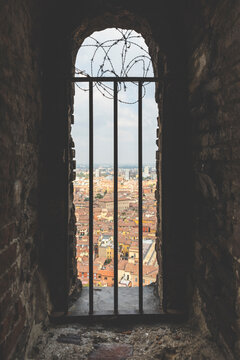 Italy, Bologna, view to the city through masonry with metal grid
