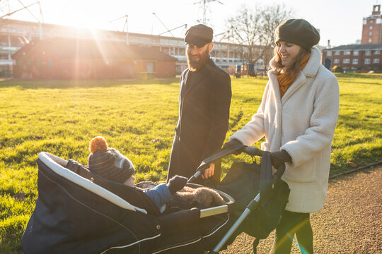Happy couple with little son in a pushchair at park