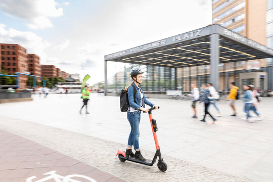 Woman riding e-scooter in the city, Berlin, Germany, Berlin, Germany