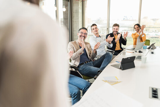 Happy business people applauding during a meeting in boardroom