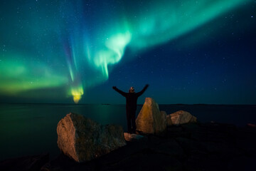 Norway, Lofoten Islands, Eggum, back view of man standing on rock admiring Northern lights