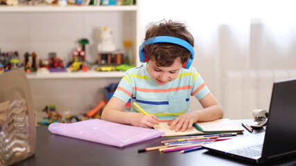 Learn on your schedule. Distance learning online education. A schoolboy boy studies at home and does school homework. A home distance learning.