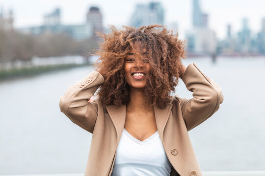 Portrait of happy young woman with curly hair, London, UK