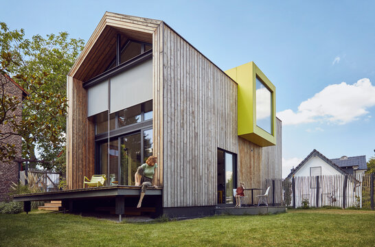 Mother looking at daughter sitting on chair outside tiny house