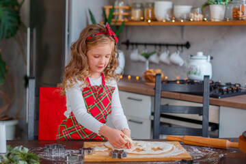 little girl making cookies for christmas in the kitchen