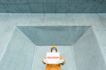 Portrait of man wearing protective clothing holding an 'isolation' sign