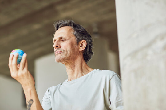 Senior man holding mini globe in a loft flat