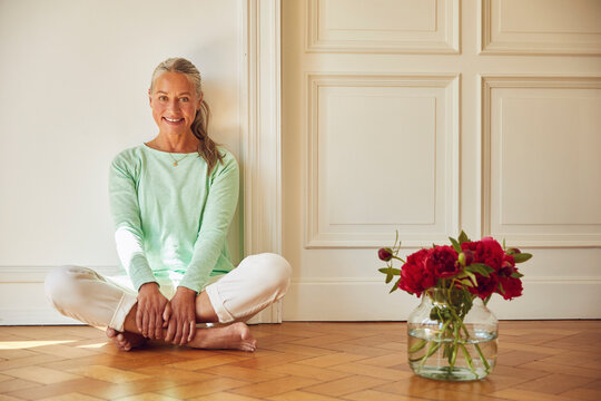Confident woman sitting on floor by flower vase at home