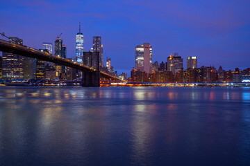 USA, New York, New York City, East River and Brooklyn Bridge at purple dawn with Manhattan skyline in background