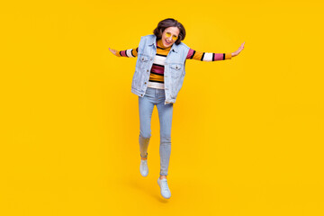 Full size photo of cool white hairdo aged lady jump wear eyewear sweater vest jeans shoes isolated on yellow background