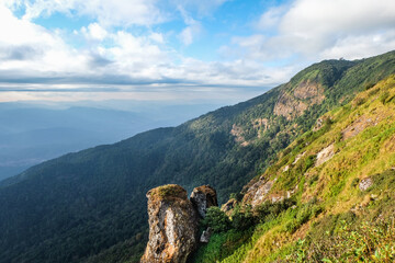 Sunlight shine on the big rocks of the hill, Adventure on the trekking trail, Sunbeam shine through the cloud to the valley and the mountain, Two boulders settle on the cliff of the mountain