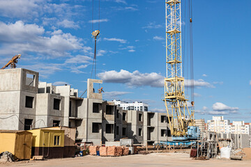 Fototapeta premium The work of tower cranes against the background of the sunset sky. Modern housing construction. Industrial engineering. Construction of mortgage housing.