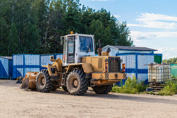 Heavy wheel loader with a bucket at a construction site. Equipment for earthworks, transportation...