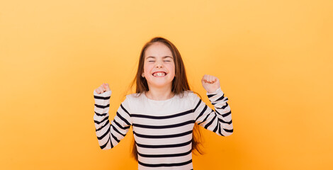 Close-up portrait of a cute little girl. Studio shot over yellow background. Childhood concept.