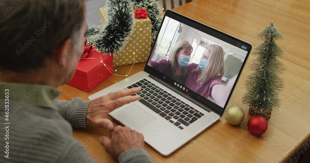 Canvas Prints Happy caucasian senior man on video call with female friends in face masks at christmas time