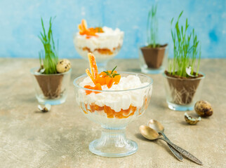 Finnish cottage cheese Easter dessert with whipped cream and dried apricots in glass bowls on a light concrete background. Happy Easter.