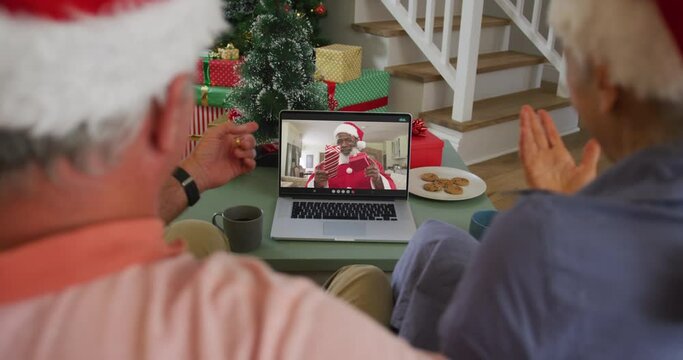 Happy caucasian senior couple on video call with santa claus at christmas time