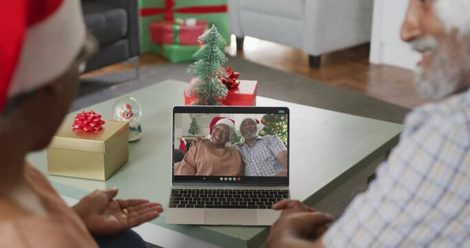 Happy african american couple on video call on laptop with senior friends at christmas time