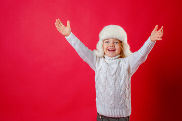 little girl in winter hat catches snow red background, new year.