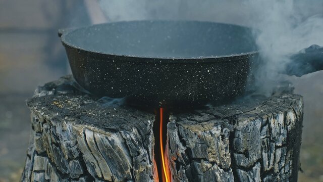 Swedish or finnish log candle. Fire burning from inside the wooden log at day. Cooking on a fire. Cooking in cauldron on Finnish Swedish log stove. Fry sunflower seeds in a pan.