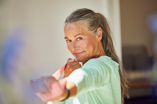 Smiling woman exercising with resistance band at home
