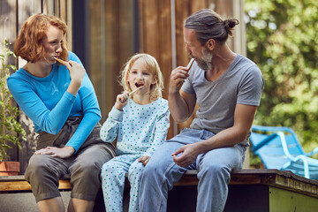 Family brushing teeth while sitting outside tiny house