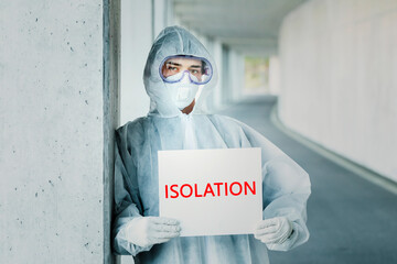 Portrait of man wearing protective clothing holding an 'isolation' sign
