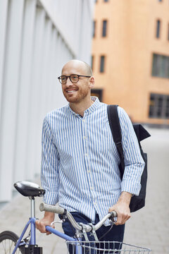 Mid adult male standing with bicycle on street