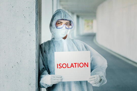 Portrait Of Man Wearing Protective Clothing Holding An 'isolation' Sign