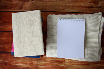 Notepad with a copy space for text, a stack of books and a warm sweater beside