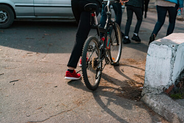 Fototapeta na wymiar Back side of a man pushing his bicycle on asphalt street. City. Urban. Outdoor. Commuting. Transportation. Road. Strollers. Sidewalk