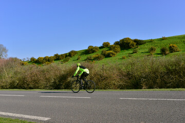 Le cycliste vert sur la route des campagnes verdoyantes françaises au ciel bleu, France