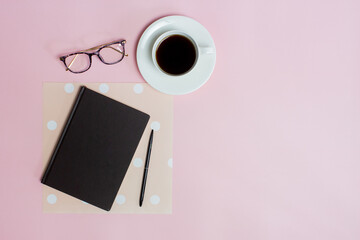 A cup of coffee with notebook over the pink background.