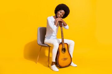 Full body profile photo of charming dark skin person sit put hands on guitar isolated on yellow...