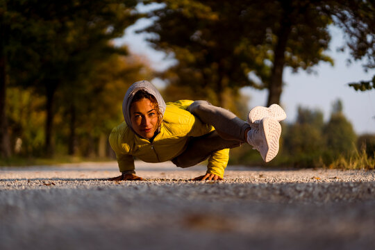 Smiling sportswoman doing handstand while exercising on road