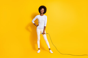 Fototapeta na wymiar Full size photo of optimistic nice short hair lady stand with mic wear white pullover trousers sneakers isolated on yellow background